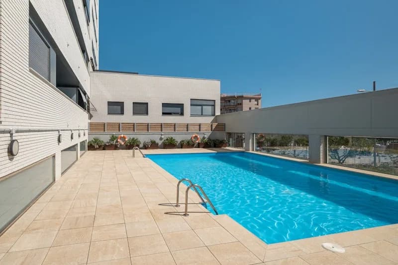 Terraza con alberca de un hotel junto a la fachada del edificio